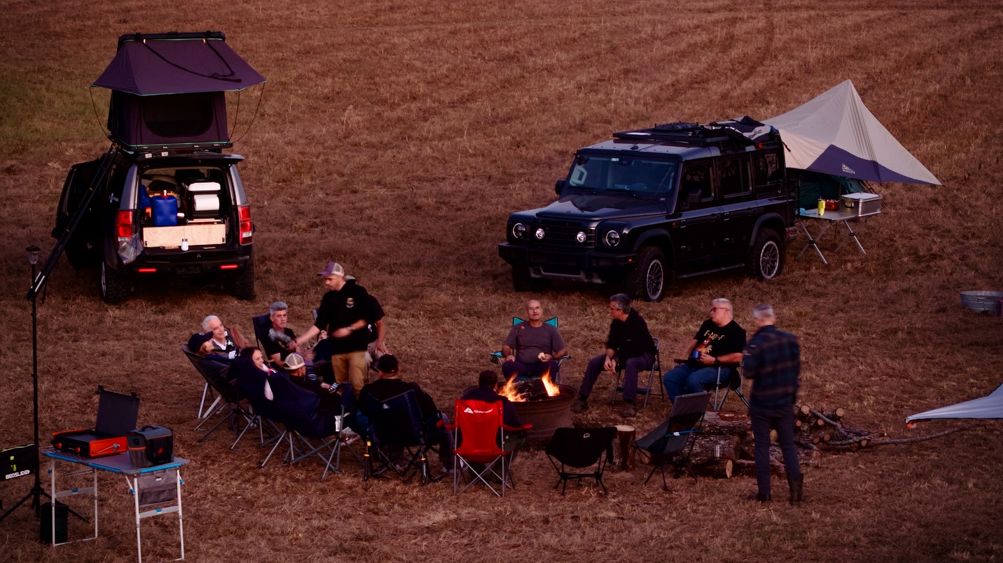 Members of the South Florida Overlanders community gathered around a campfire at dusk